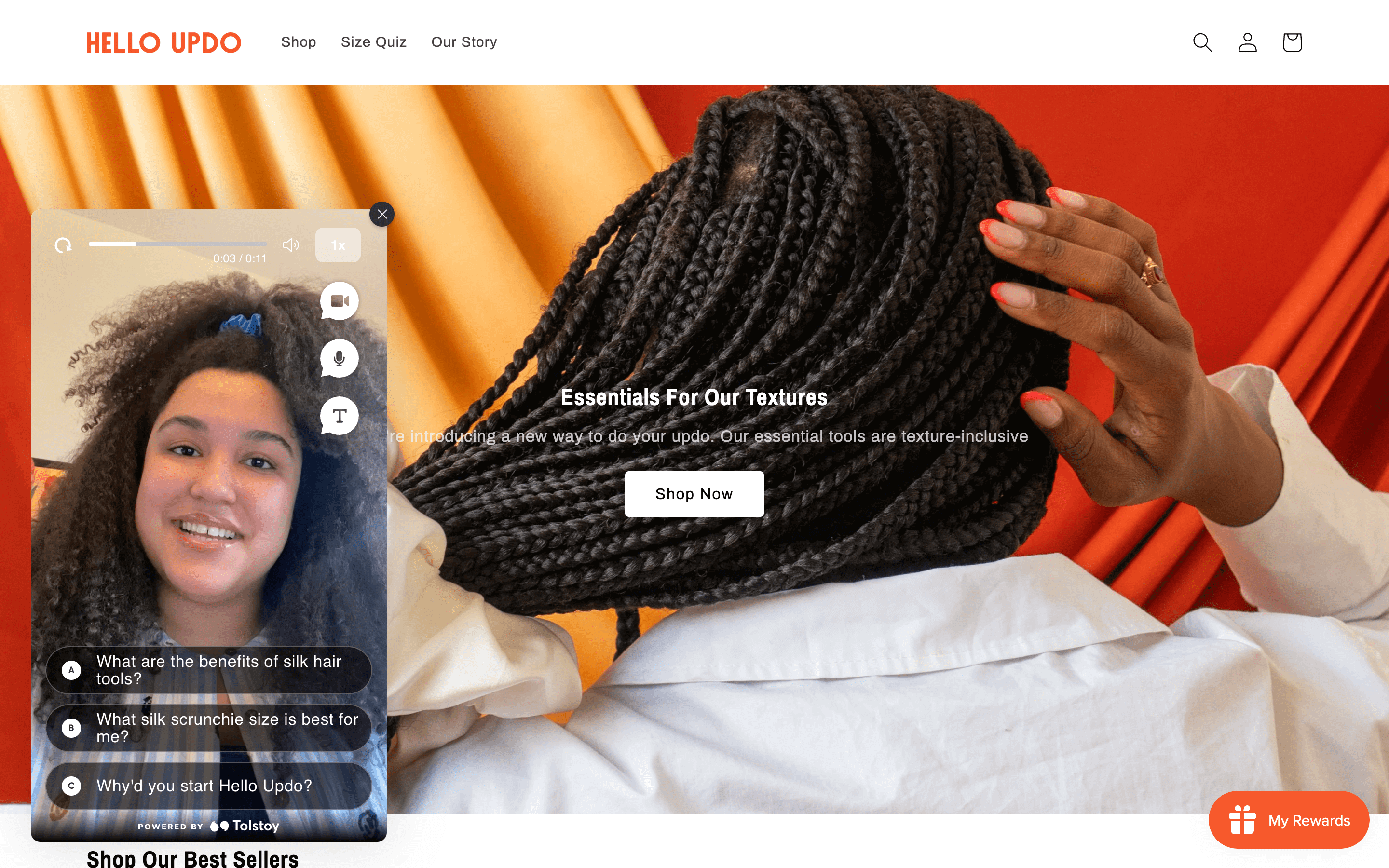 Women Ecommerce Entrepreneurs–A screenshot from Hello Updo’s homepage. There is an image of the back of a woman’s head with braids and a large silk scrunchie in her hair. The text on top reads, “Essentials For Our Texture”. On the left of the page, there is a video of Magdaline, the founder welcoming people to the website. 