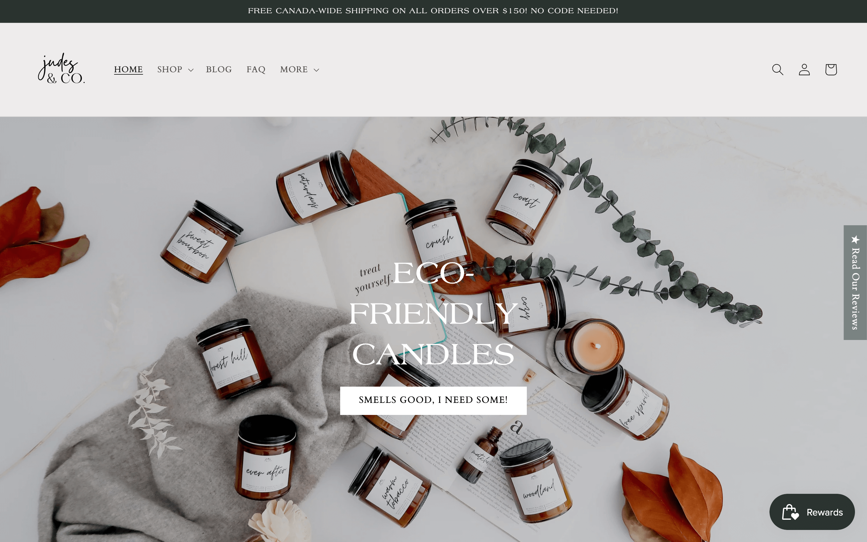 Women Ecommerce Entrepreneurs–A screenshot from Judes & Co. homepage. There is a background image of several candles laying on a white surface surrounded by books, blankets, foliage, and plants. The text on top reads, “Eco-Friendly Candles. Smells GOOD, I Need Some!!!”