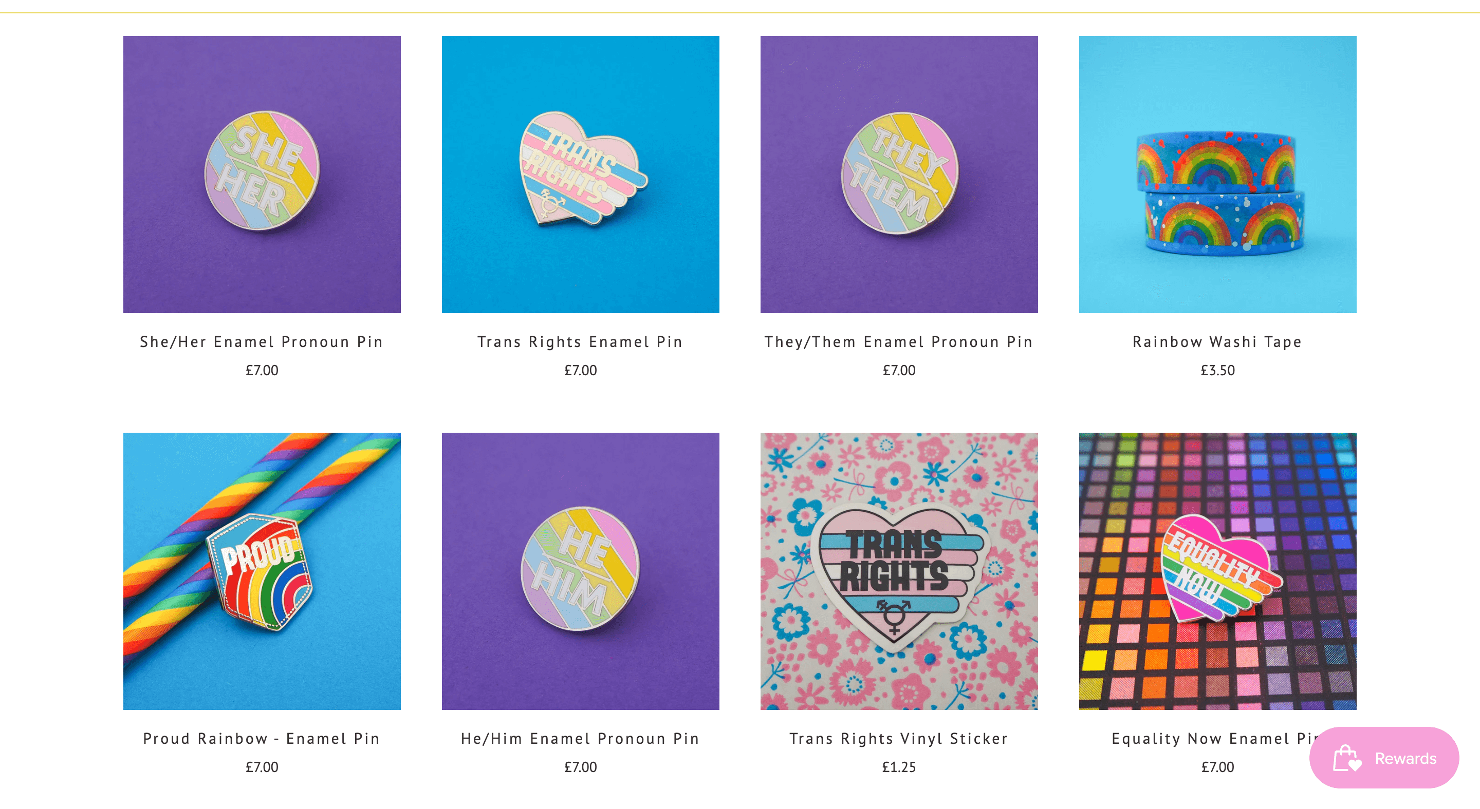 An image of Hand Over Your Fairy Cakes’ Pride collection product catalog page on its website. There are images and descriptions of 8 products: She/Her enamel pronoun pin, Trans Rights enamel pin, They/Them enamel pronoun pin, Rainbow washi tape, Proud Rainbow enamel pin, He/Him enamel pronoun pin, Trans Rights vinyl sticker, and the Equality Now enamel pin.