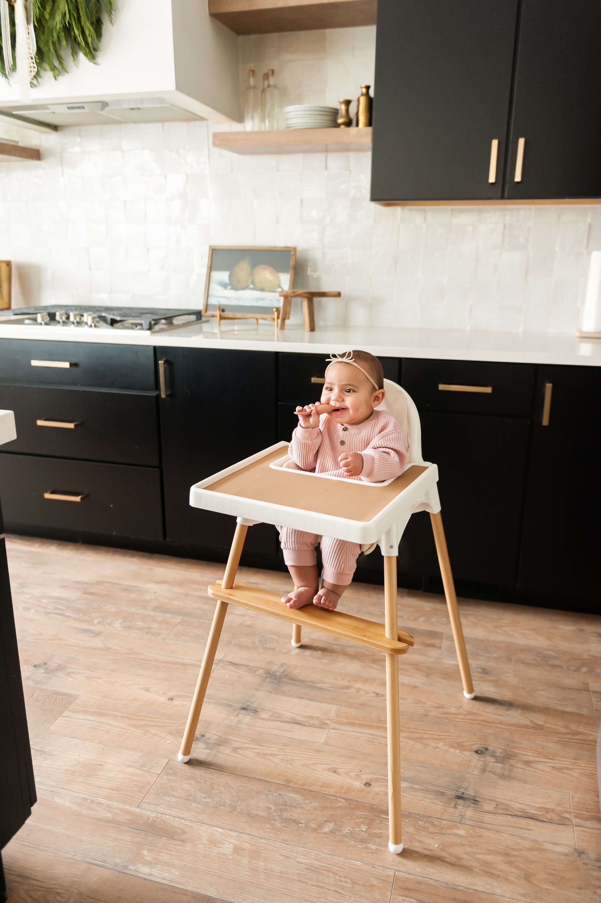 image of a baby on an IKEA high chair smiling with a baby spoon in her mouth