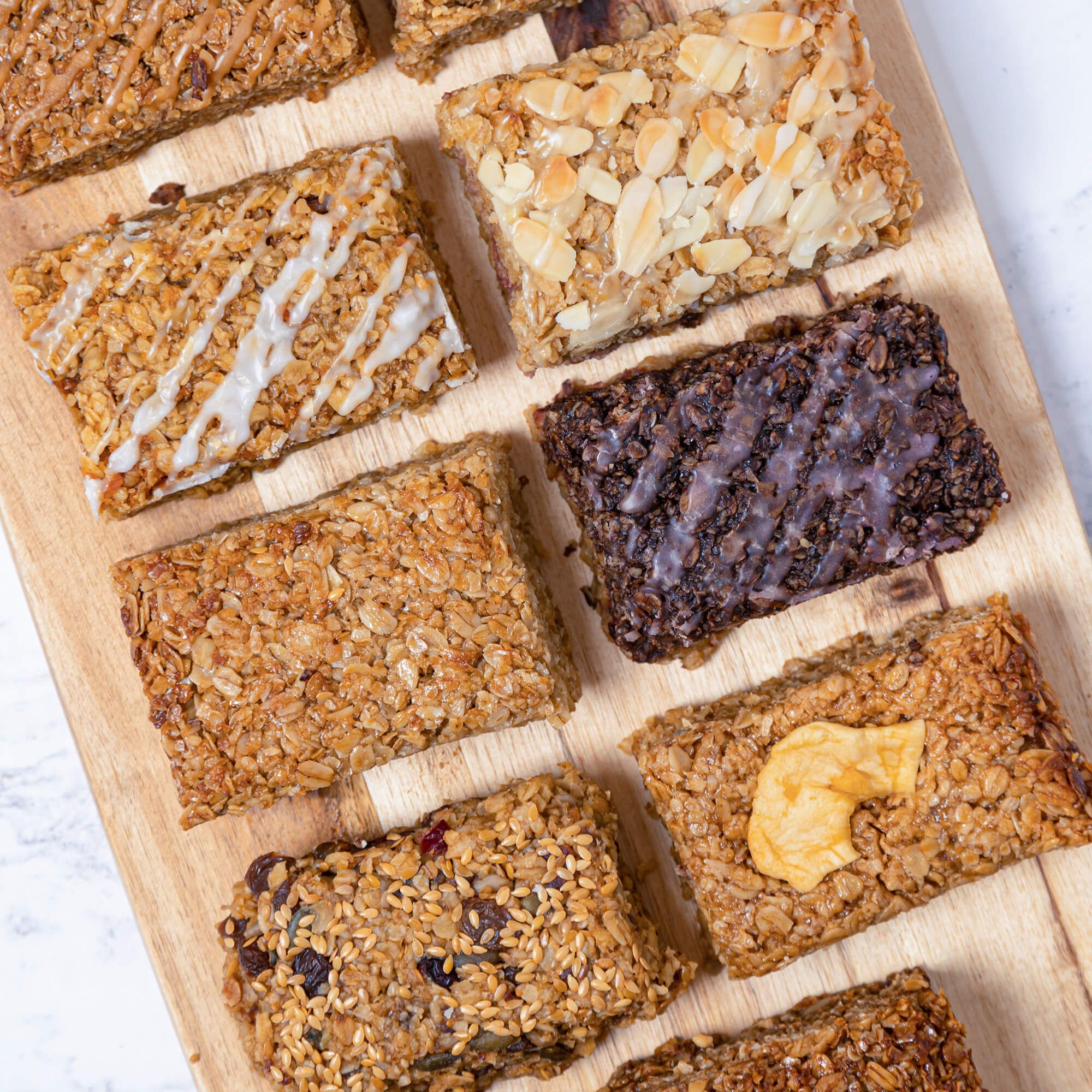 A bird’s eye view image of 8 oat-based flapjacks on a wooden cutting board. 