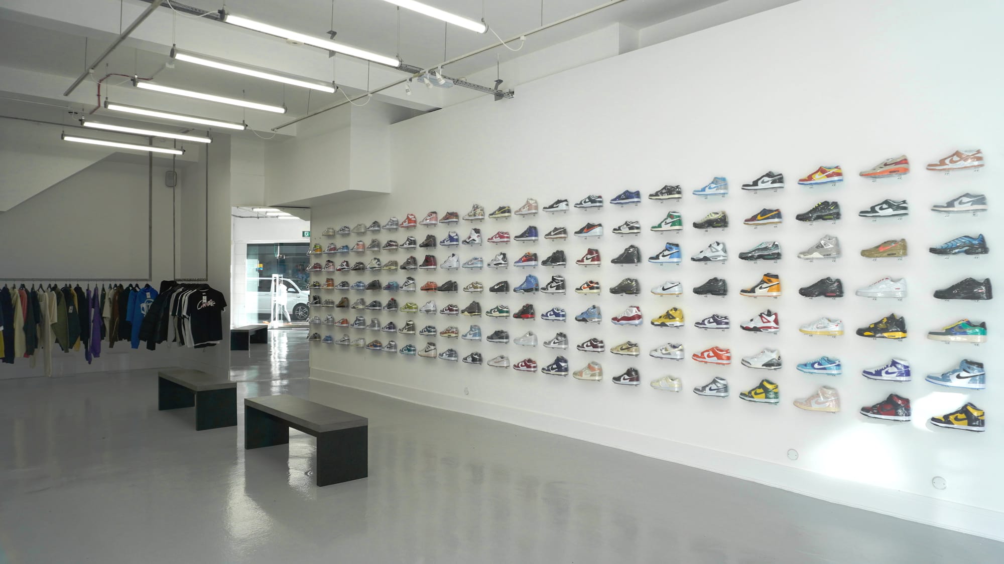 An image of the Side Kicks store. It shows a white wall filled with dozens of sneakers on display.