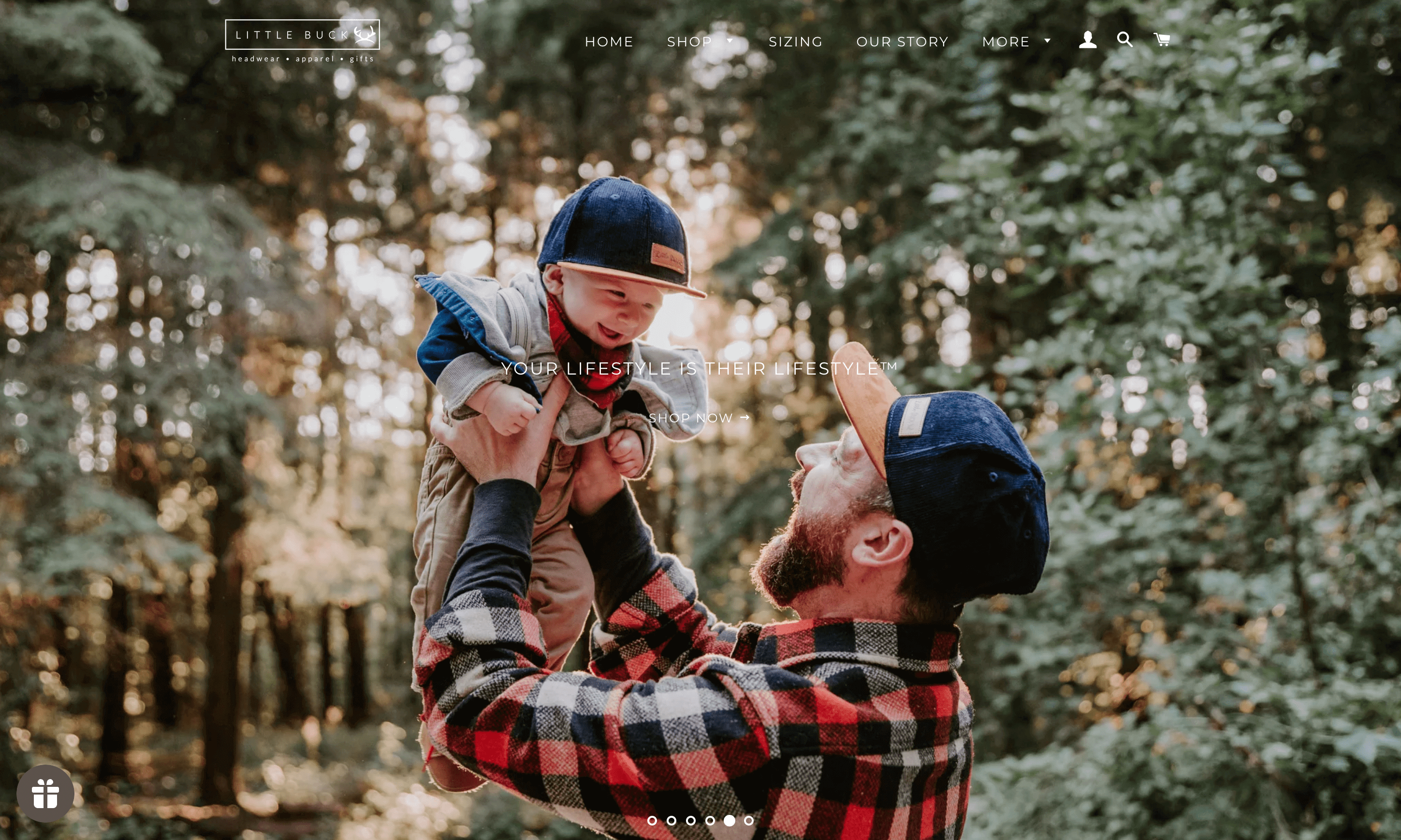 A screenshot of Little Buck’s homepage showing a dad holding his baby in matching snapback navy blue Little Buck hats. 